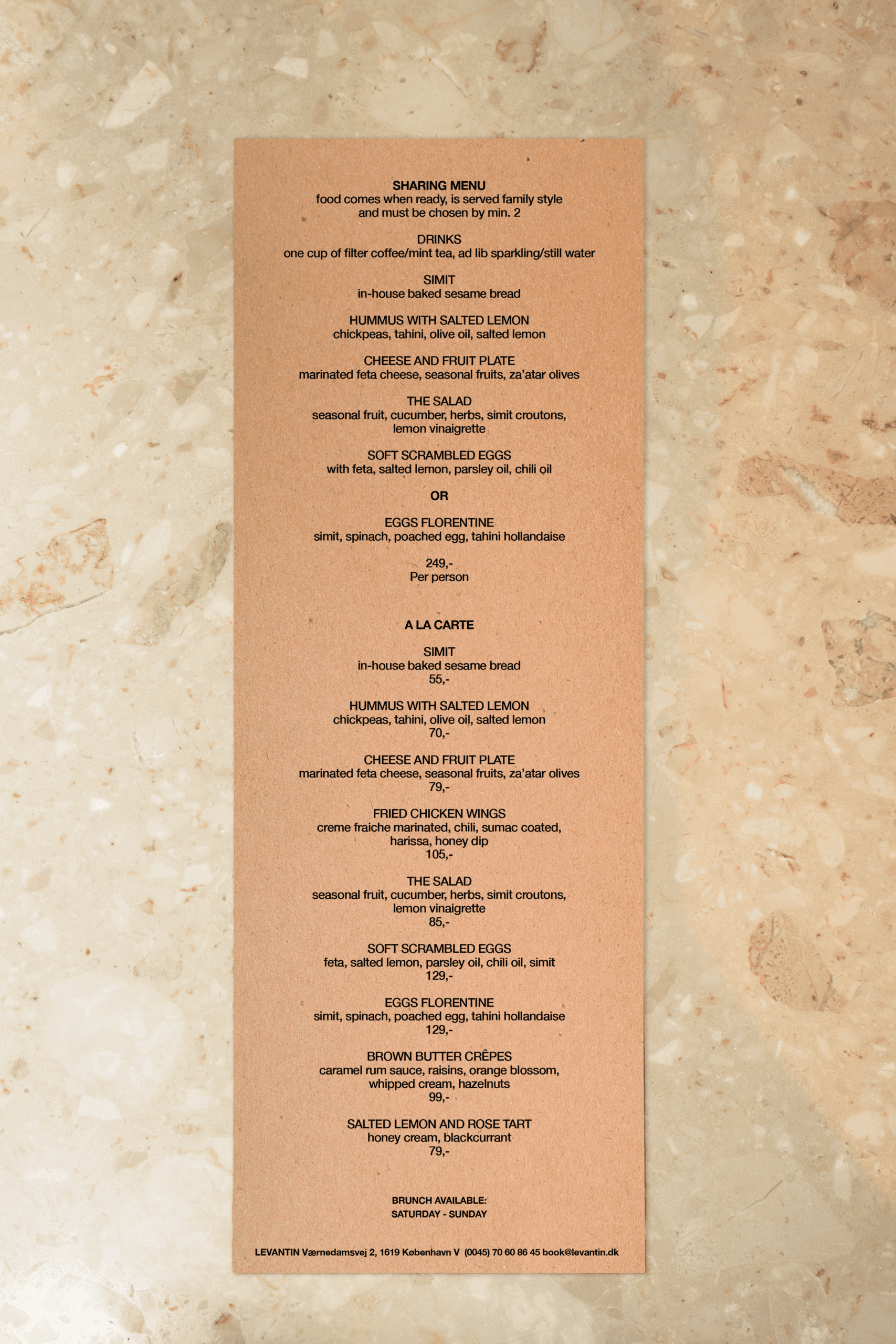 Marble table with a brown paper menu with brunch dishes served at Levantin, middle eastern bistro in copenhagen